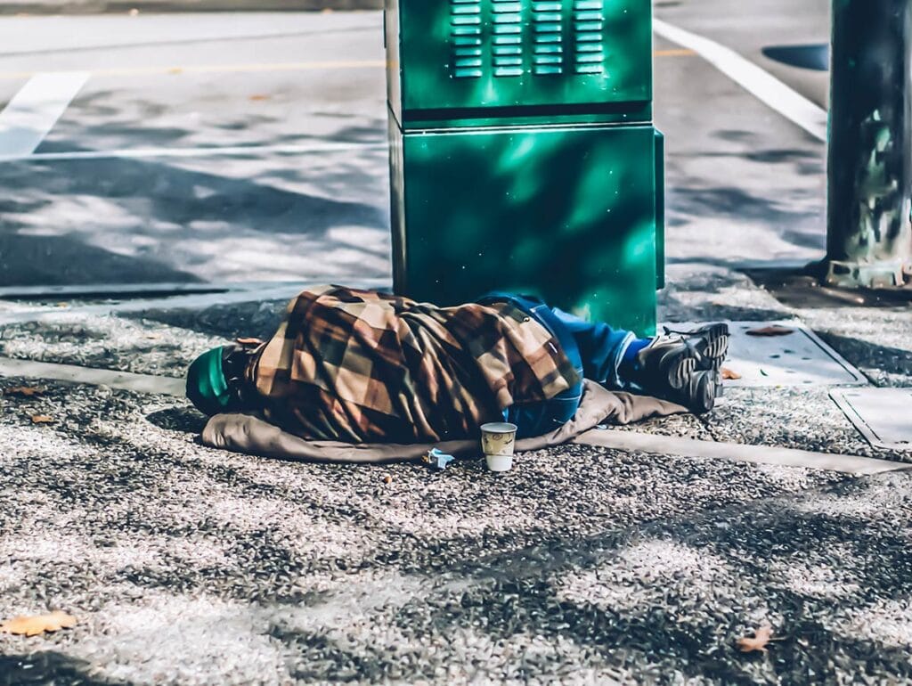 A picture of a homeless man sleeping on the sidewalk in Downtown Vancouver