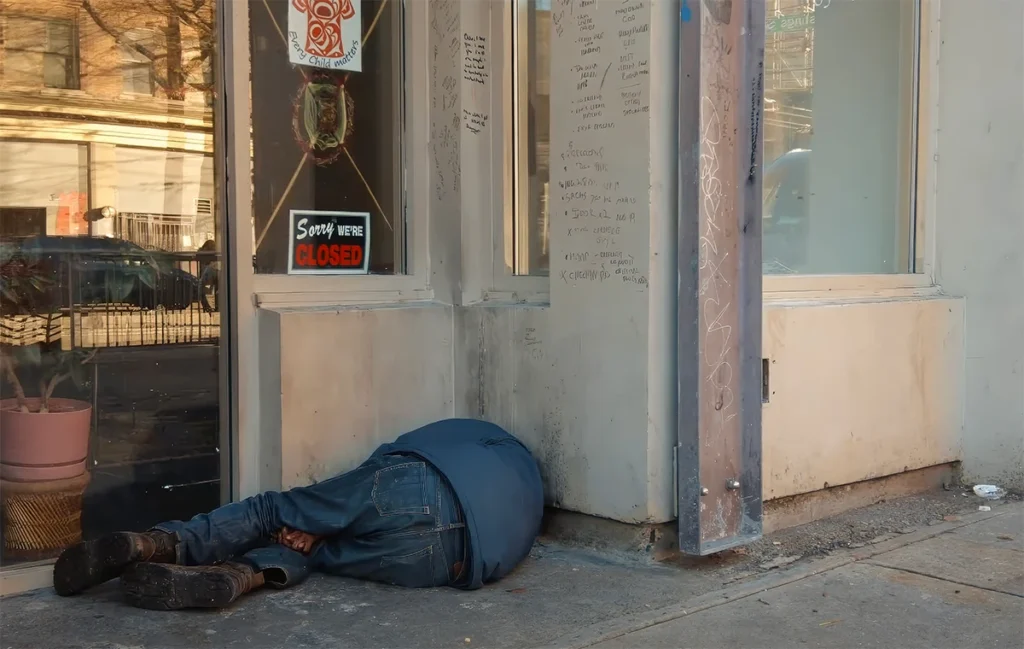 Image capturing a person laying on the sidewalk of Vancouver Downtown Eastside next to a closed business