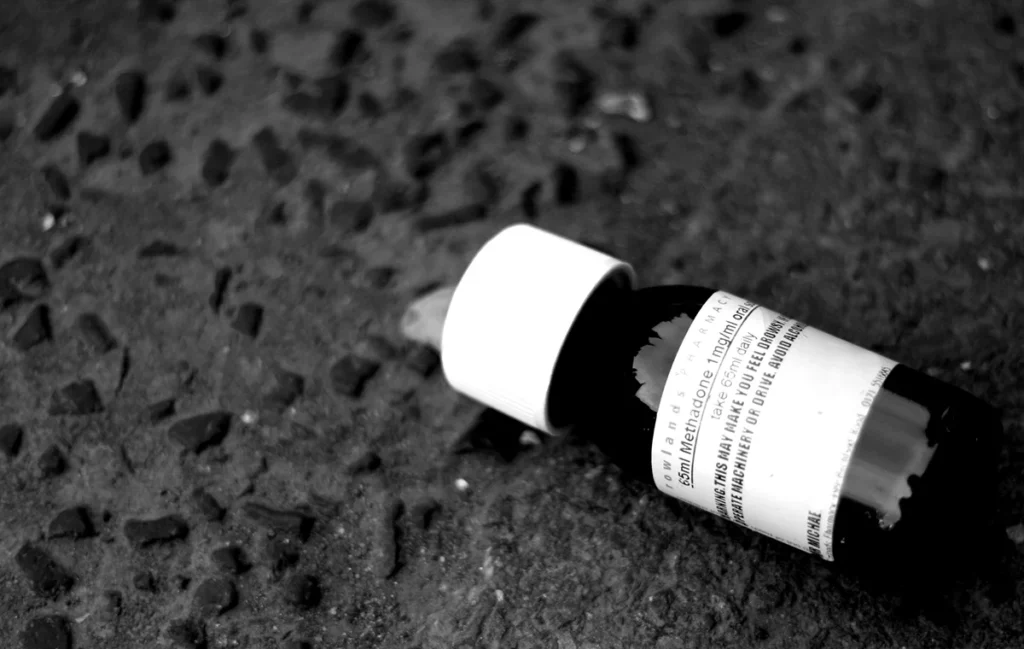 Picture of a bottle of prescription medication Methadone laying on a sidewalk