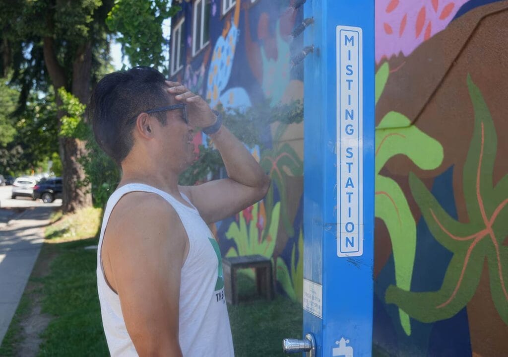 Photo of a man using the City of Vancouver's misting station installed in the Downtown Eastside are during the heat wave