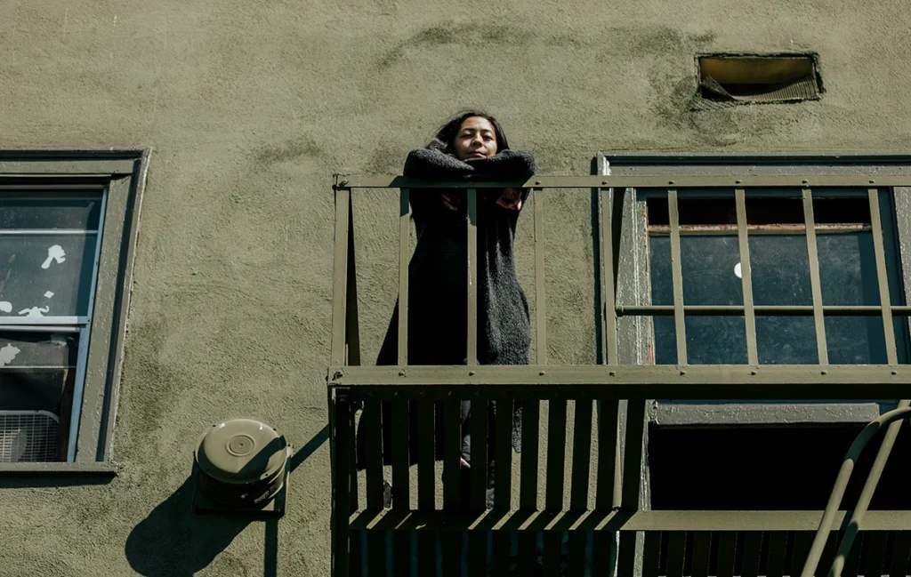 Picture of a woman standing on the balcony of social housing in Downtown Eastside Vancouver