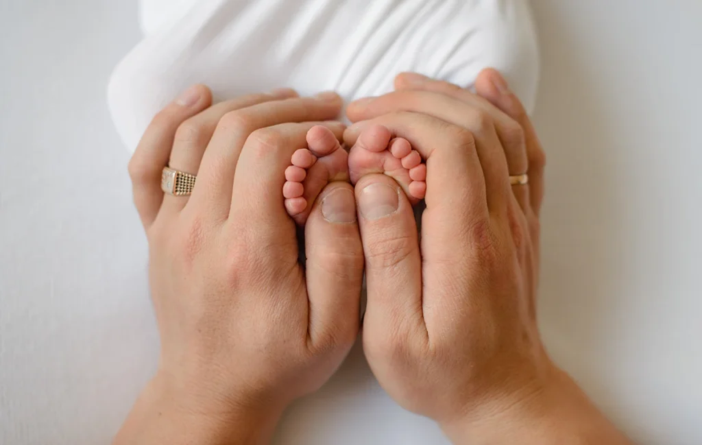 Image of mother's hands holding feet of a newborn child