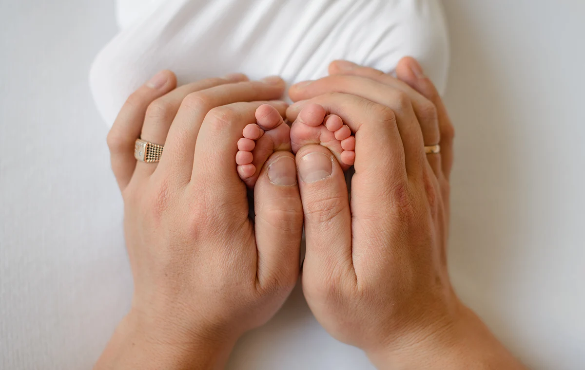 Image of mother's hands holding feet of a newborn child