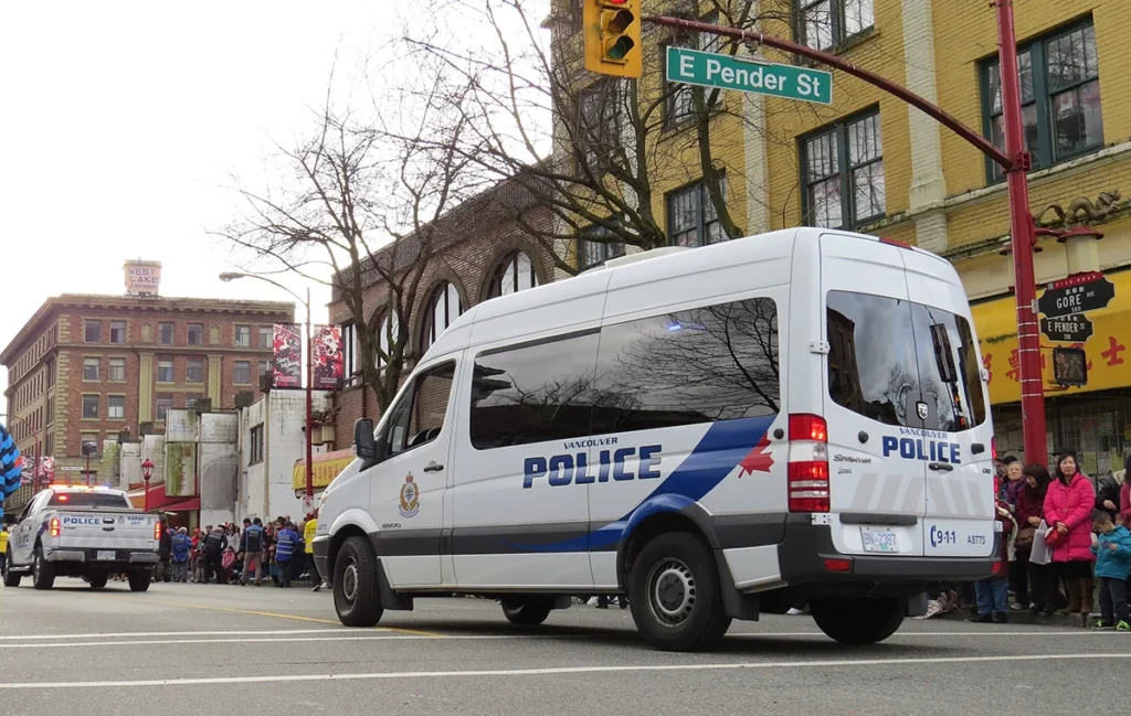 Image of Vancouver Police Department standing in the middle of the street with people behind it