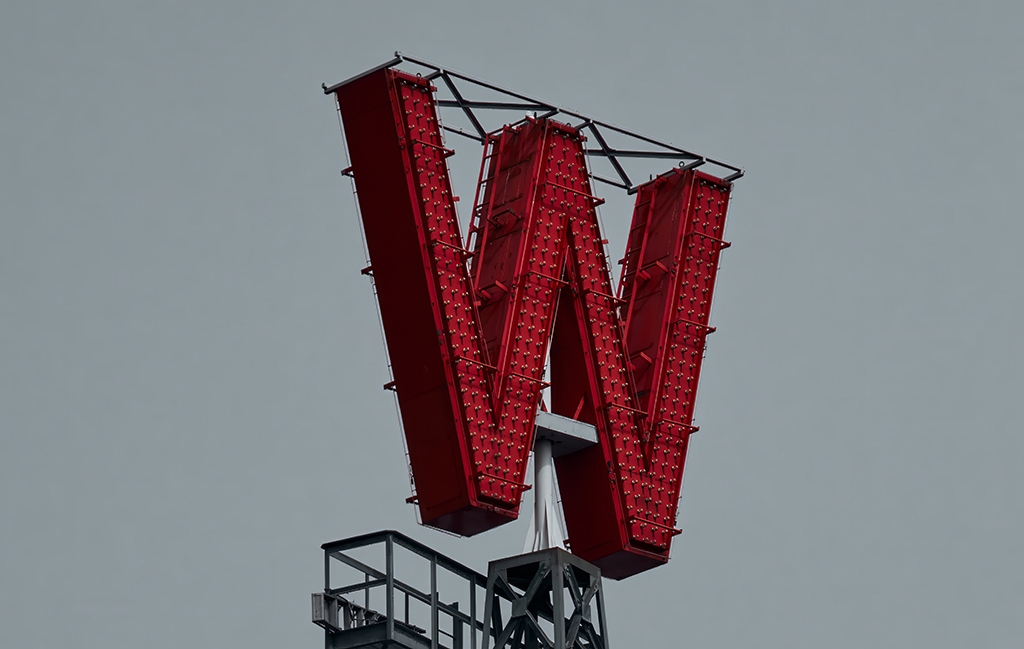 Close-up of the iconic red 'W' sign atop the historic Woodward's building in Vancouver, symbolizing the site's legacy and transformation over the years.