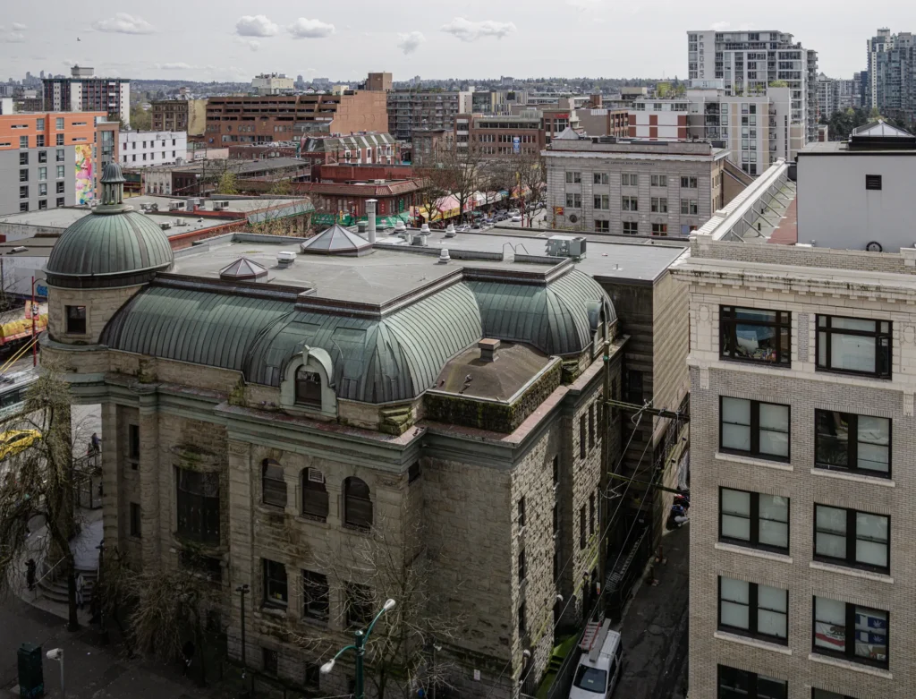 High-angle view of the historic Carnegie Community Centre showing its stone facade and green copper roof dome in Vancouver's Downtown Eastside.